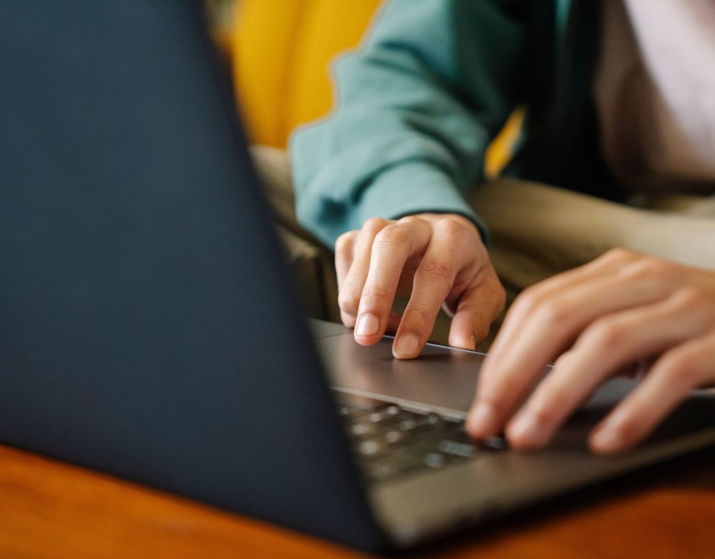 Crop unrecognizable distance employee surfing internet on netbook while working on project at desk in room